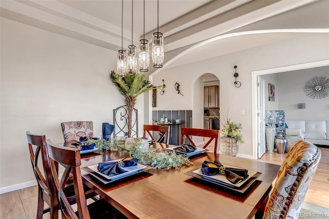 dining area with light hardwood / wood-style floors, a raised ceiling, and a notable chandelier