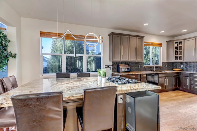 kitchen with a breakfast bar, light stone countertops, plenty of natural light, and pendant lighting