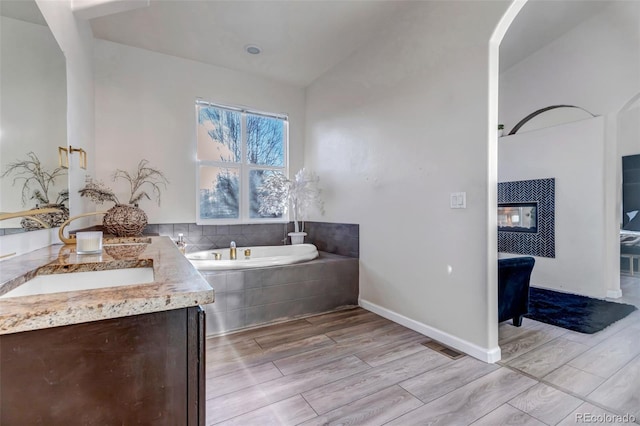 bathroom with tiled bath and vanity