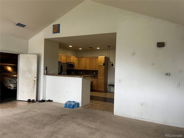 14400 Albrook Dr Unit 88, Denver, CO 80239 - kitchen with freestanding refrigerator, stainless steel microwave, dark countertops, light carpet, and high vaulted ceiling