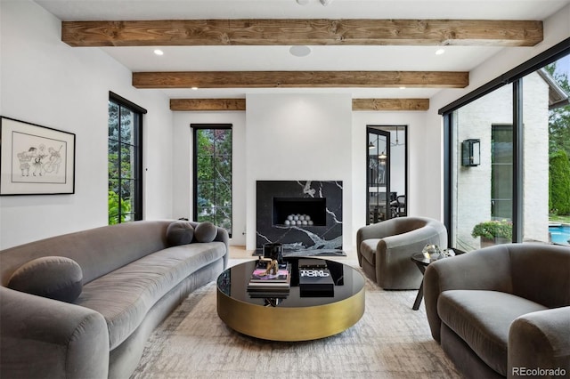 living room featuring beamed ceiling and a premium fireplace