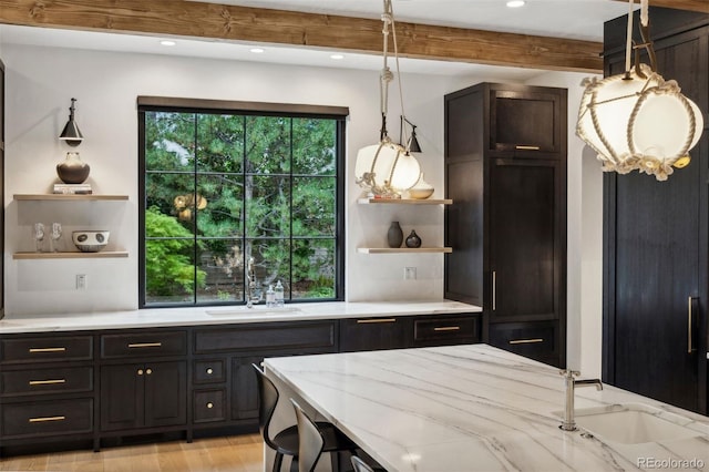 kitchen with beamed ceiling, decorative light fixtures, light stone counters, and sink