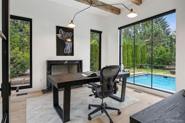 office featuring beamed ceiling, light hardwood / wood-style floors, and plenty of natural light