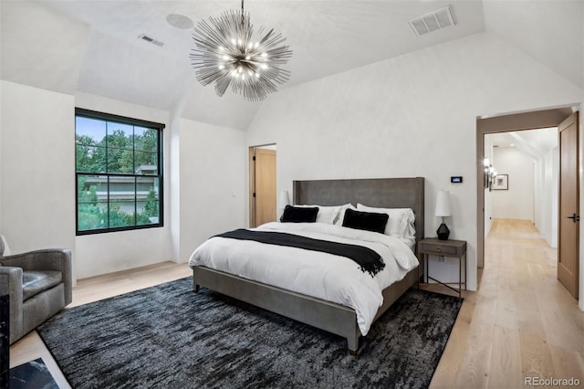 bedroom featuring a chandelier, vaulted ceiling, and light wood-type flooring