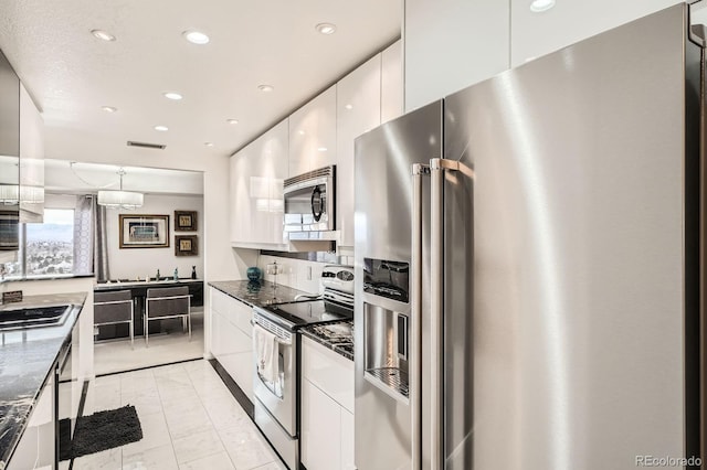 kitchen with recessed lighting, appliances with stainless steel finishes, white cabinetry, dark stone countertops, and modern cabinets