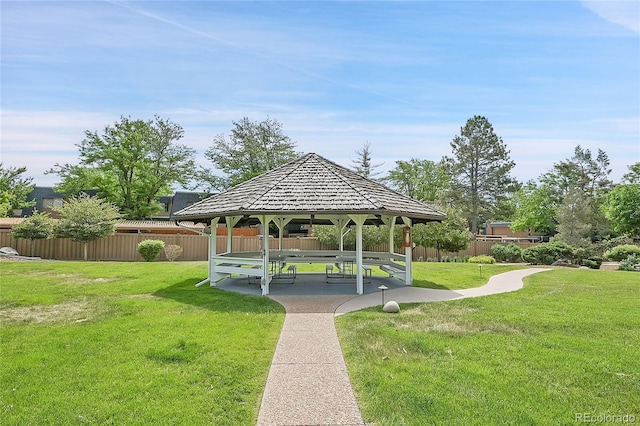 view of community with fence, a lawn, and a gazebo