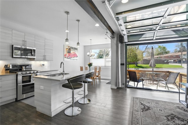 12497 W Virginia Ave, Lakewood, CO 80228 - kitchen with a sink, stainless steel appliances, a kitchen bar, dark wood-style floors, and modern cabinets