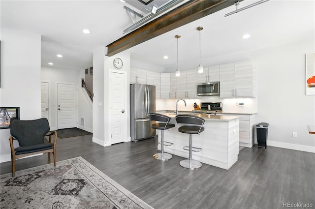 12497 W Virginia Ave, Lakewood, CO 80228 - kitchen with a breakfast bar area, recessed lighting, baseboards, dark wood-style flooring, and appliances with stainless steel finishes