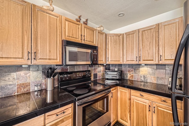 kitchen featuring stainless steel appliances, light brown cabinets, a textured ceiling, and decorative backsplash