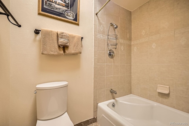 bathroom featuring tiled shower / bath combo and toilet