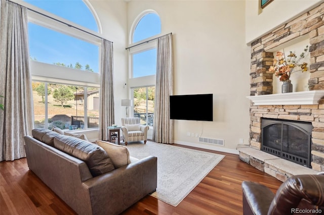 living room featuring a fireplace, dark hardwood / wood-style floors, and a towering ceiling