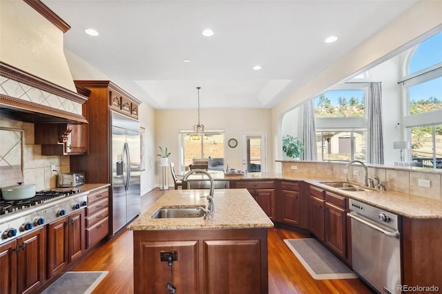 kitchen with stainless steel appliances, sink, a center island with sink, and dark wood-type flooring