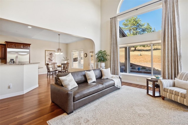 living room with dark wood-type flooring and a towering ceiling