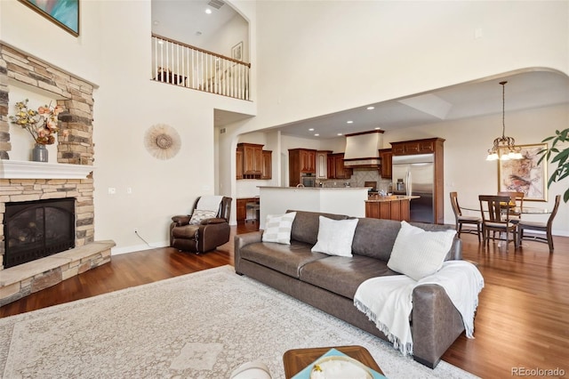 living room featuring a fireplace, dark hardwood / wood-style floors, a notable chandelier, and a high ceiling