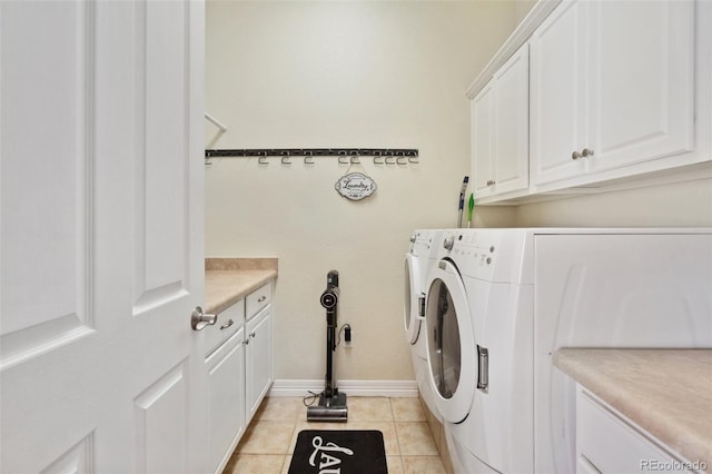 clothes washing area with cabinets, washing machine and dryer, and light tile patterned floors