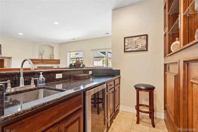 kitchen featuring wine cooler, dark stone counters, light tile patterned flooring, and sink