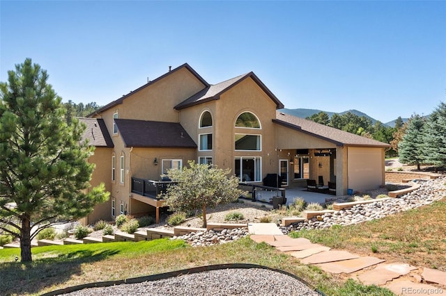 back of property with a mountain view and a patio