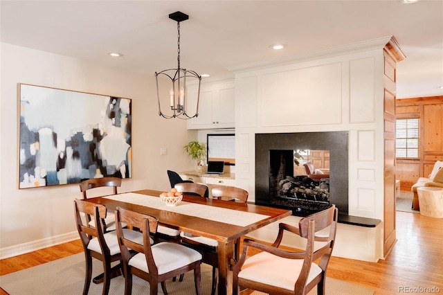 dining room featuring a multi sided fireplace, recessed lighting, light wood-style flooring, and an inviting chandelier