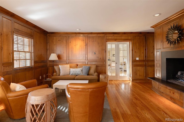 living room with french doors, a fireplace with raised hearth, and wood finished floors