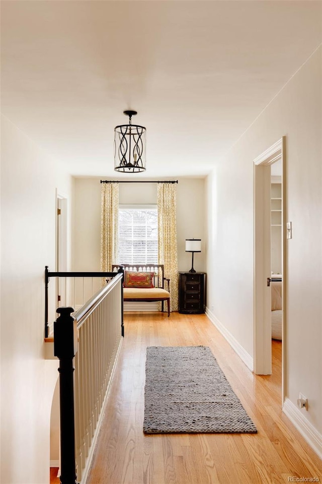 corridor with light wood-type flooring, baseboards, and an upstairs landing