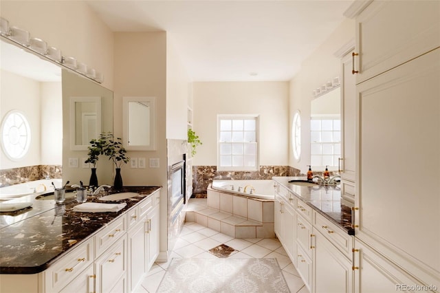 bathroom with tile patterned floors, two vanities, a bath, and a sink