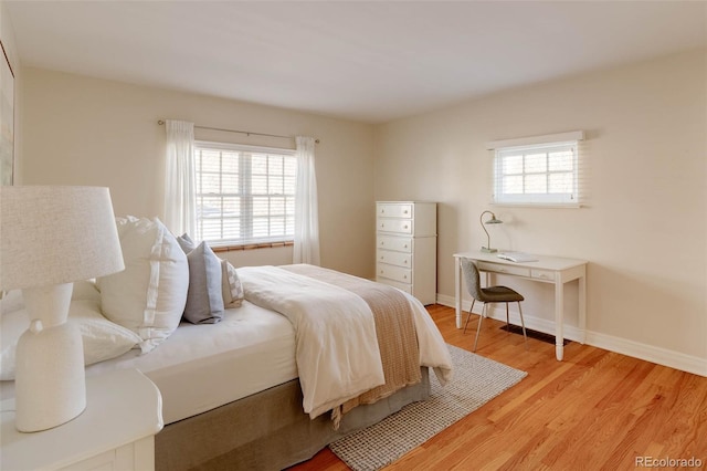 bedroom with light wood finished floors, multiple windows, and baseboards