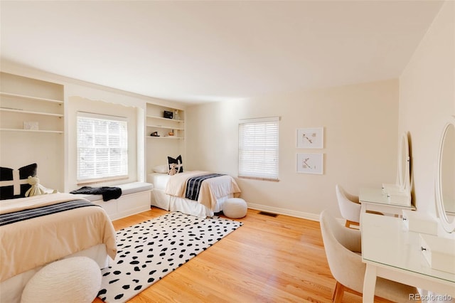 bedroom featuring light wood finished floors, visible vents, and baseboards