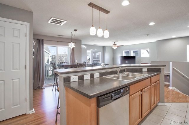 kitchen featuring sink, a breakfast bar, dishwasher, a center island with sink, and decorative light fixtures