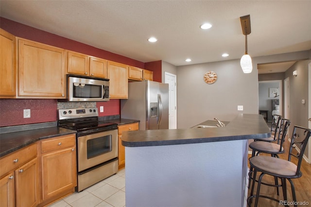 kitchen featuring dark countertops, tasteful backsplash, a breakfast bar, stainless steel appliances, and recessed lighting