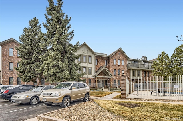 view of front of home with uncovered parking, fence, and brick siding