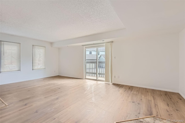 unfurnished room featuring light wood-style floors, baseboards, and a textured ceiling