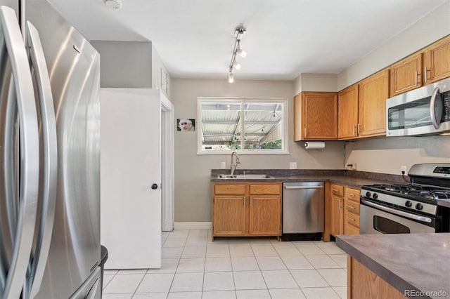 3154 N Columbine St, Denver, CO 80205 - kitchen featuring appliances with stainless steel finishes, light tile patterned floors, dark countertops, rail lighting, and brown cabinets