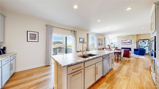 55 Morgan Cir, Erie, CO 80516 - kitchen featuring dishwasher, light wood-style flooring, a fireplace, open floor plan, and an island with sink