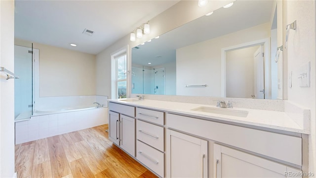 55 Morgan Cir, Erie, CO 80516 - full bathroom with double vanity, a garden tub, wood finished floors, and an enclosed shower