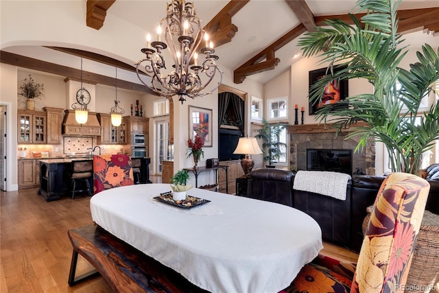 8002 Galileo Way, Littleton, CO 80125 - dining area featuring light wood-style flooring, arched walkways, beam ceiling, a glass covered fireplace, and a notable chandelier