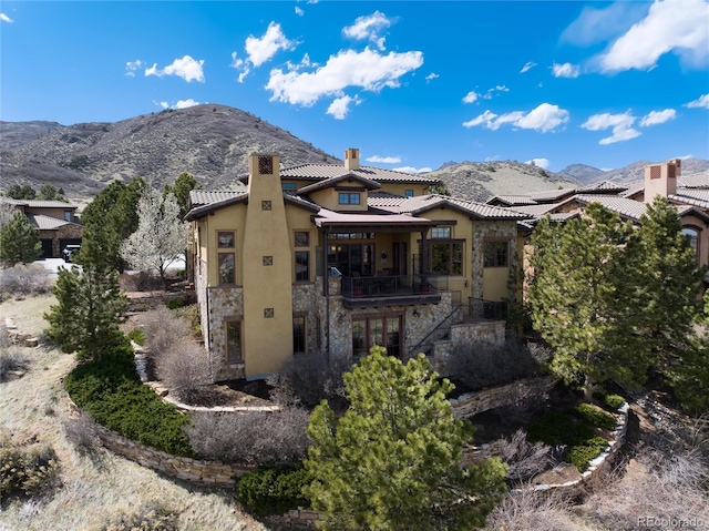 8002 Galileo Way, Littleton, CO 80125 - rear view of house with stone siding, a chimney, a mountain view, and stucco siding
