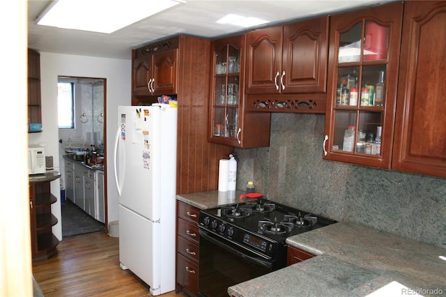 kitchen featuring white appliances, wood finished floors, brown cabinets, tasteful backsplash, and glass insert cabinets