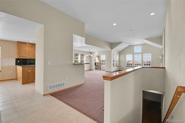 hallway featuring vaulted ceiling, light colored carpet, and an inviting chandelier