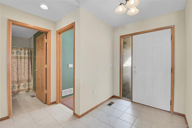 tiled entryway with a notable chandelier