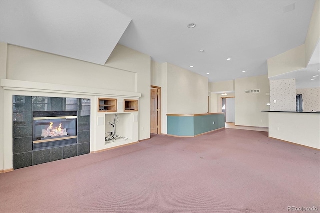 unfurnished living room featuring built in shelves, a tiled fireplace, and carpet flooring