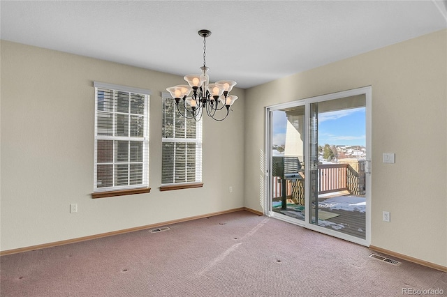 carpeted spare room with an inviting chandelier