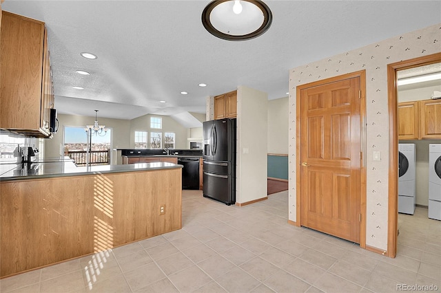 kitchen with kitchen peninsula, decorative light fixtures, washer and dryer, a notable chandelier, and black appliances