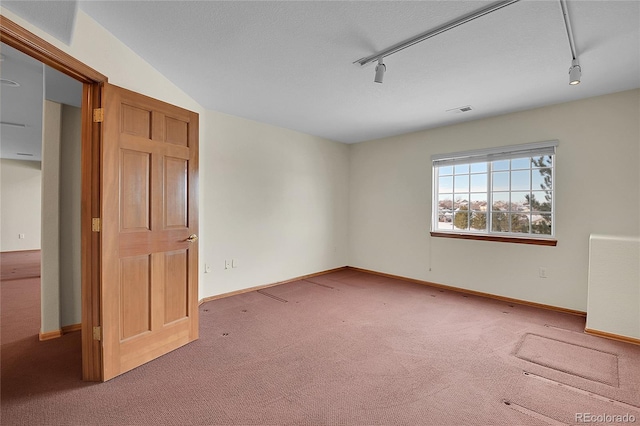 carpeted empty room featuring rail lighting and radiator