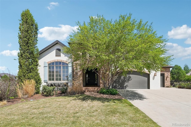 obstructed view of property featuring a garage, driveway, a front yard, and stucco siding