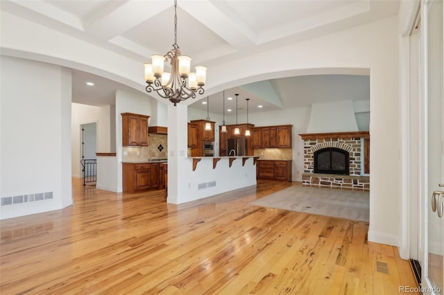 unfurnished living room featuring a chandelier, light wood-style floors, beamed ceiling, recessed lighting, and coffered ceiling