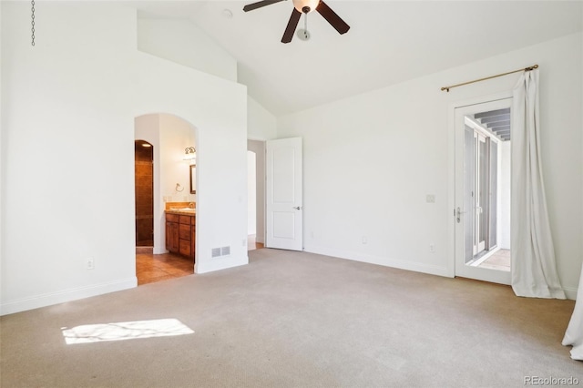 unfurnished bedroom featuring light carpet, arched walkways, access to exterior, baseboards, and high vaulted ceiling