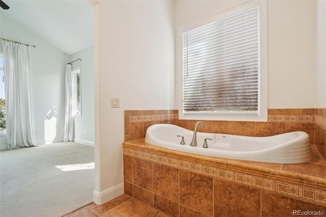 bathroom with plenty of natural light, a garden tub, lofted ceiling, and tile patterned flooring