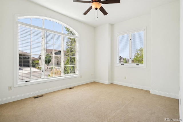 unfurnished room featuring light colored carpet, baseboards, and a ceiling fan