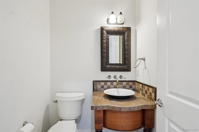half bath featuring tasteful backsplash, toilet, and vanity