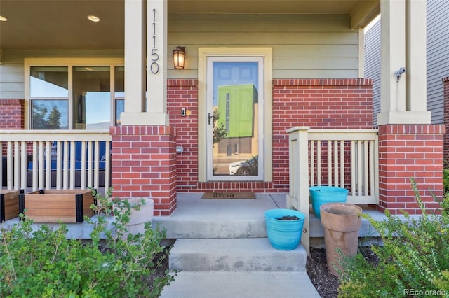 property entrance with covered porch and brick siding